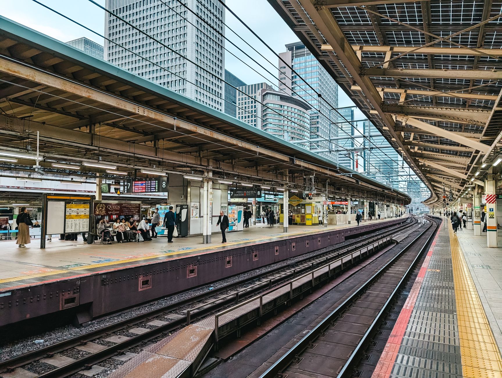 A bustling railway station platform with people waiting, showcasing urban transportation and architecture.