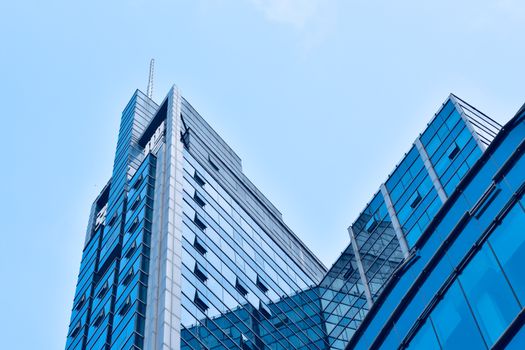 A low angle view of a sleek modern skyscraper in an urban setting with reflective glass windows.