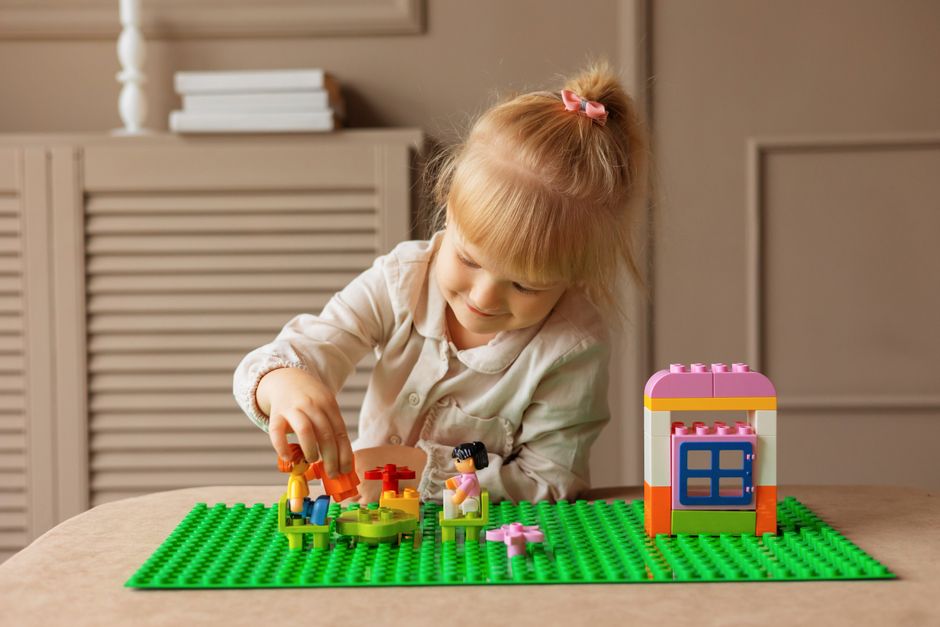 Young girl engaged in building with colorful blocks. Indoor creative activity.