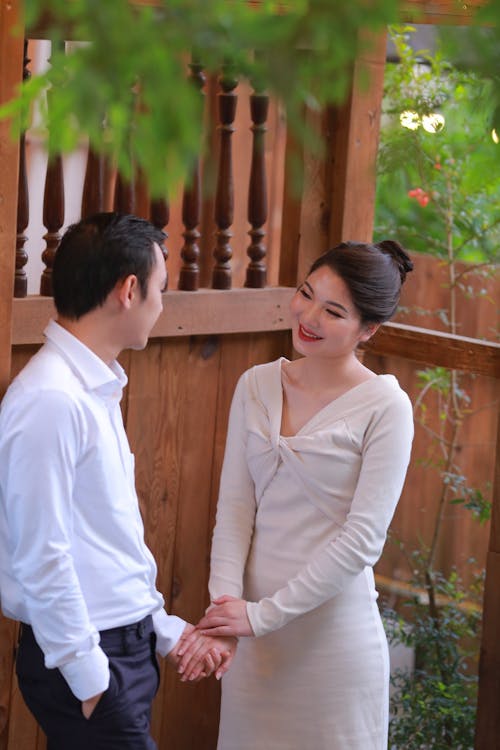 A man and woman are holding hands in front of a wooden fence