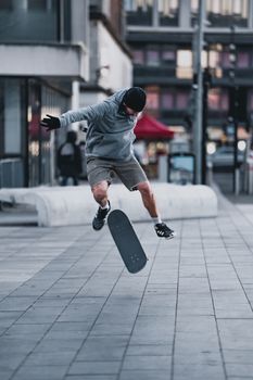 Skateboarder executes a mid-air trick on a city sidewalk, showcasing skill and urban lifestyle.. skateboarder, executes, tric