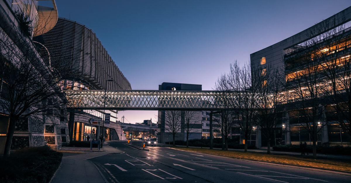 City street with a modern bridge connecting two buildings at twilight.