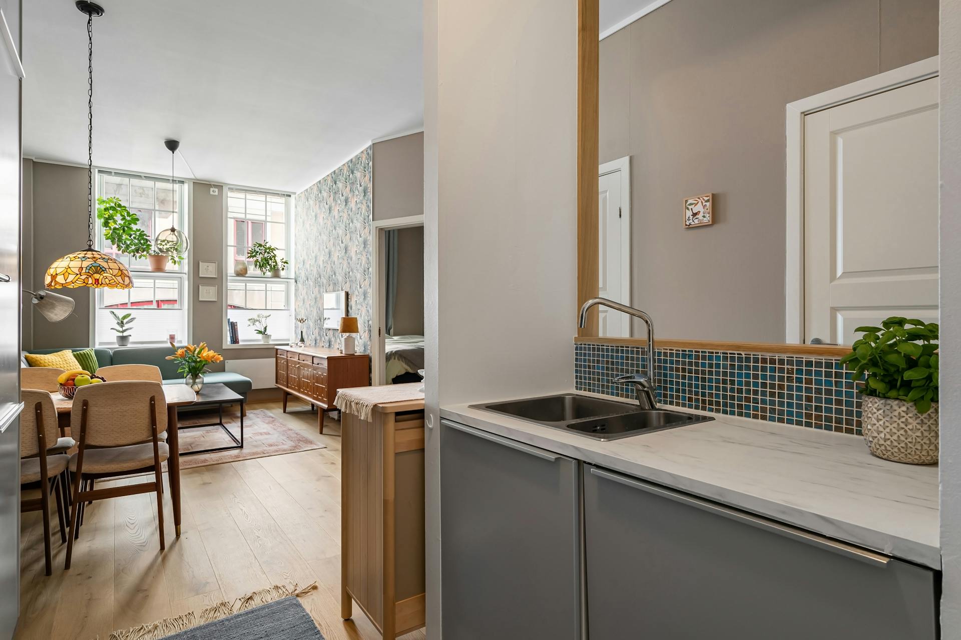 Interior of a cozy modern apartment featuring a bright living room and sleek kitchen.