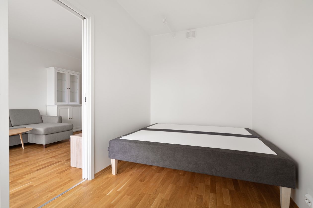 Small bedroom with open visible floor and a bed on legs.