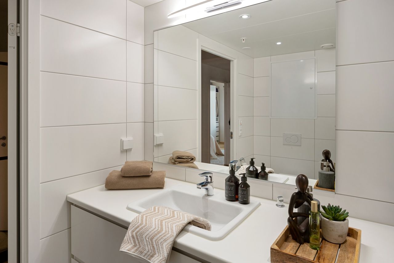 Clean white bathroom vanity with folded towels, round mirror, and styled counter