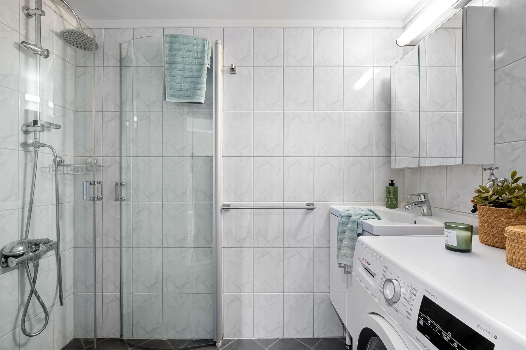 Scandinavian-style bathroom with integrated laundry area and organized storage