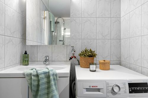 Free A clean and modern bathroom with integrated laundry area and elegant decor. Stock Photo