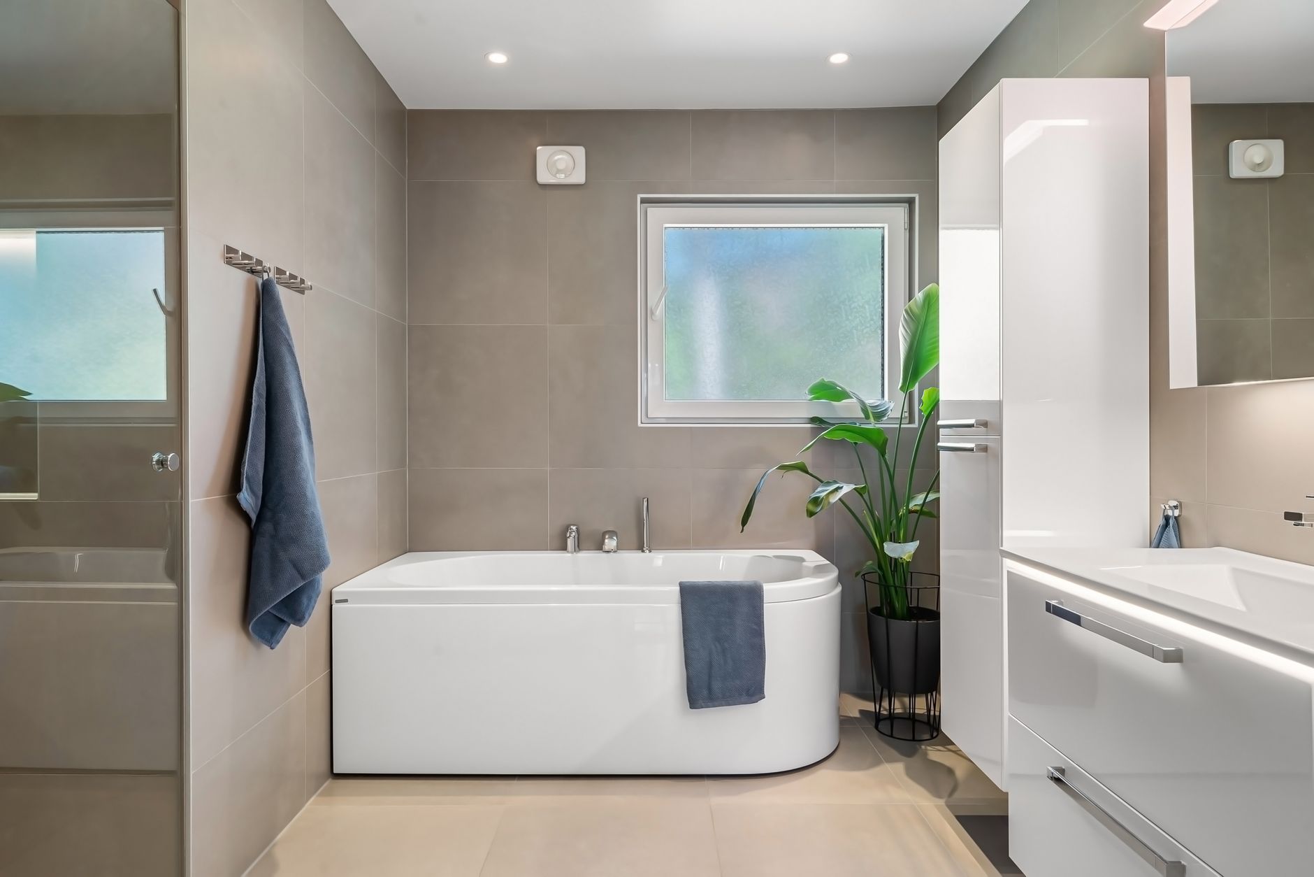 Penceresiz bir banyoda nem ve buhar sorununu gideren modern bir havalandırma fanı ve banyo iç mekanı.