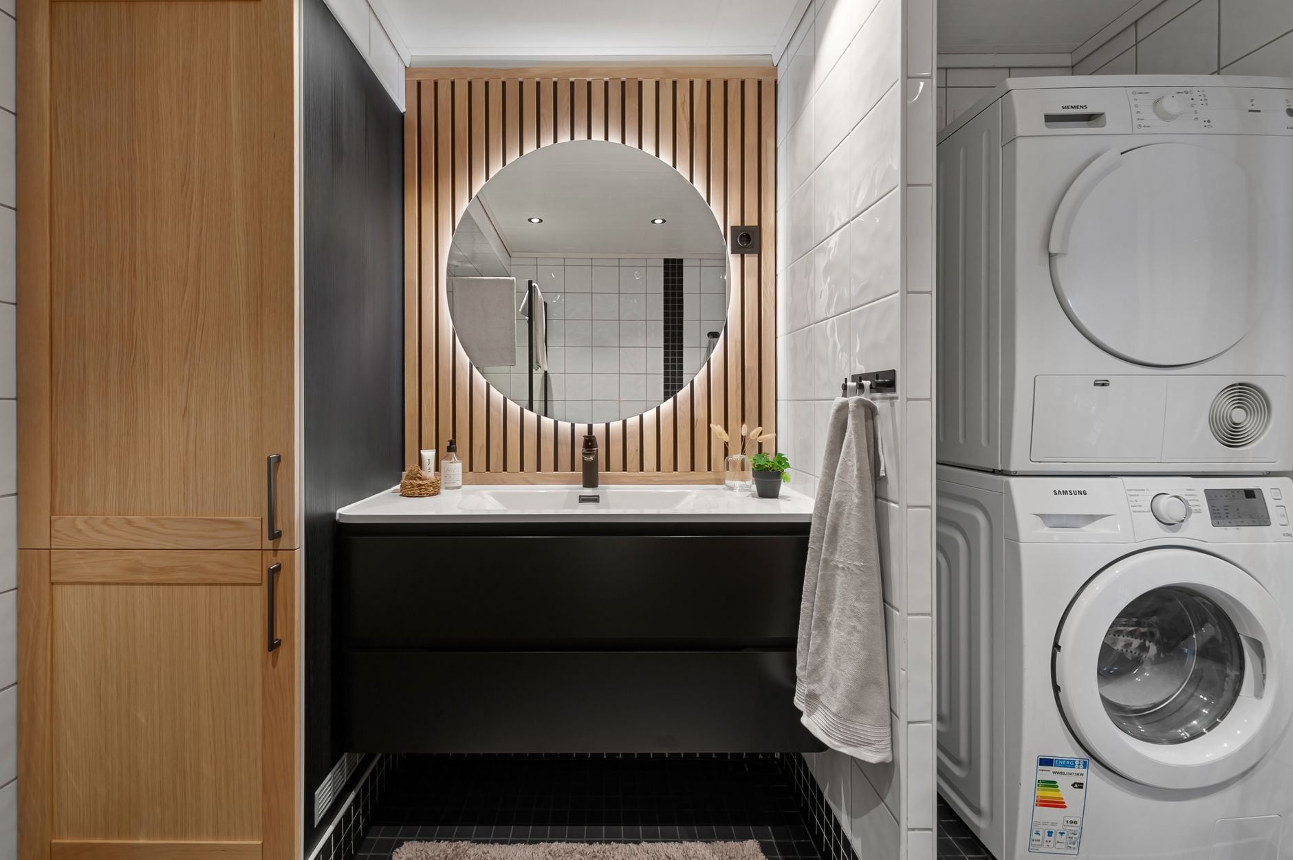 How to Compare Washer and Dryer Sets at Home Depot Sleek bathroom featuring a round mirror, modern sink, and integrated washer and dryer.