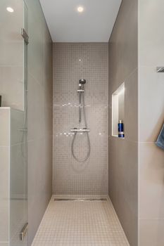 Contemporary shower with glass and tiled surfaces in a minimalist bathroom.