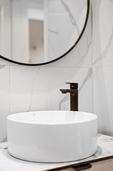 A stylish minimalist bathroom setup featuring a round sink and sleek faucet.