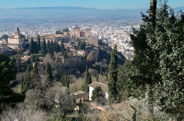 Stunning view of the Alhambra with Granada cityscape in Spain, surrounded by lush cypress trees. — arriving in Granada
