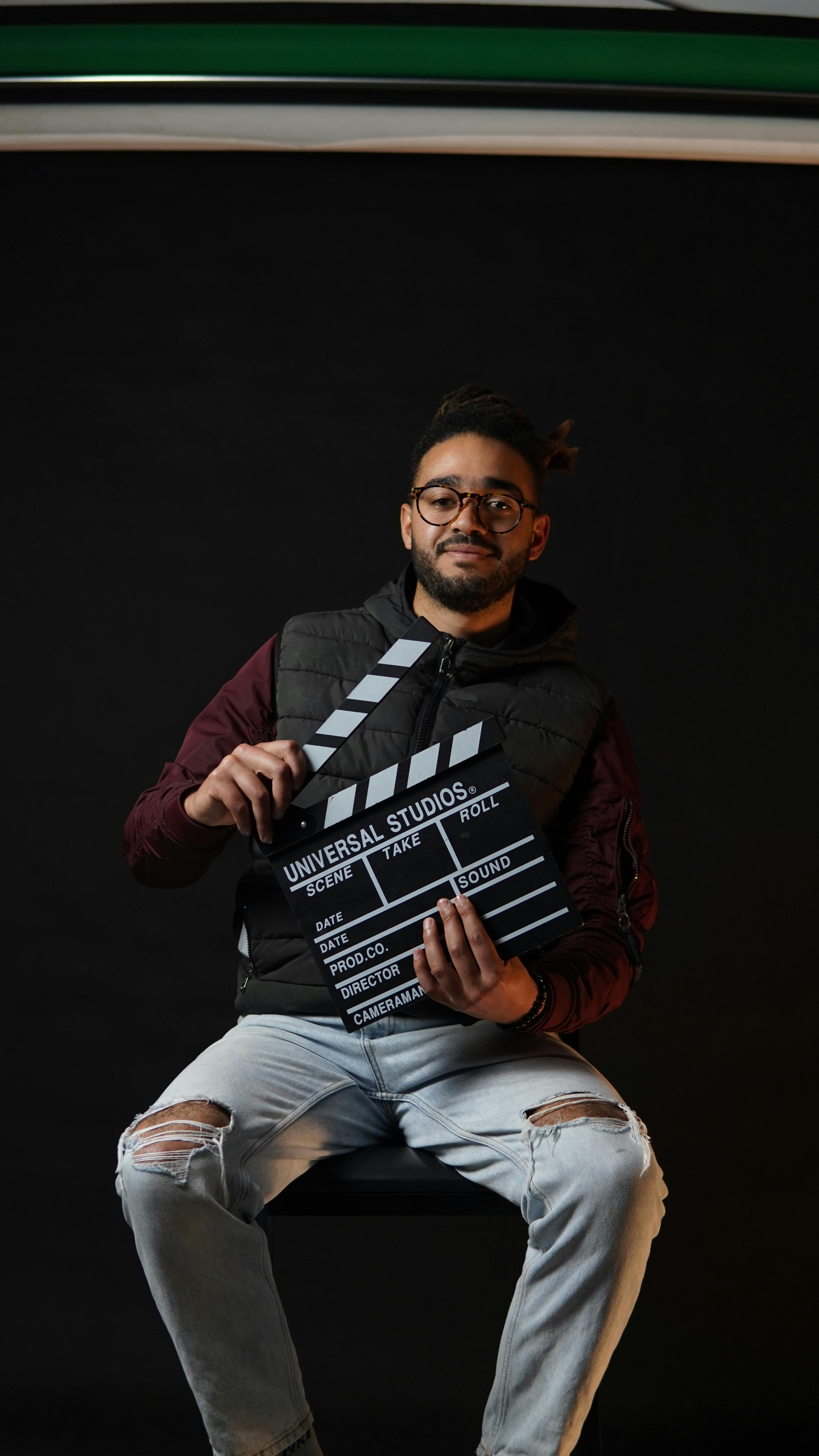 Casual portrait of a man with a clapperboard in a studio setting.