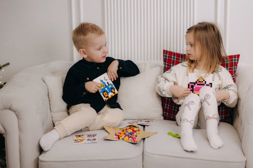 Free Two children sitting on a couch playing with toys Stock Photo