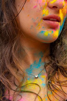 Vibrant close-up of a woman's face and neck with colorful paint and a silver necklace, capturing festive spirit.