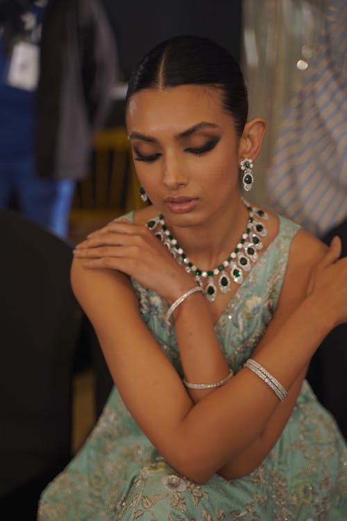 A model wearing a blue dress and jewelry