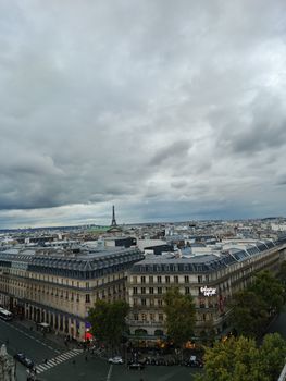 Stunning aerial cityscape of Paris with the Eiffel Tower under a cloudy sky.