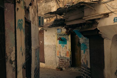 Free Explore a narrow urban alleyway with weathered buildings and artistic murals for a rustic street vibe. Stock Photo