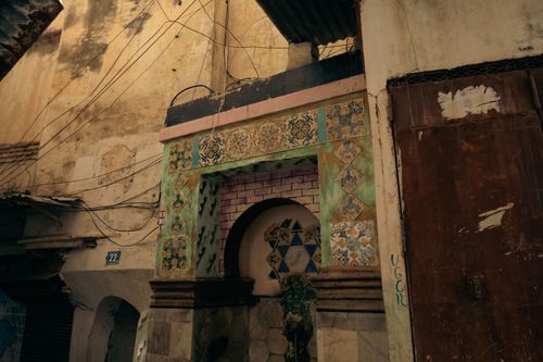 Free Detailed mosaic and rustic architecture in a narrow alleyway, exuding a vintage urban charm. Stock Photo