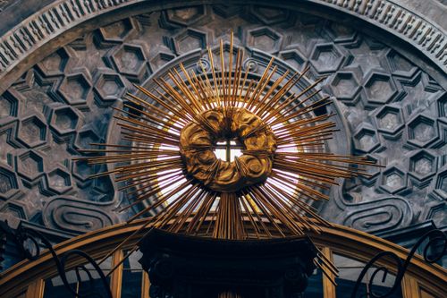 Free Ornate golden sunburst with cross inside a cathedral dome, showcasing intricate design. Stock Photo