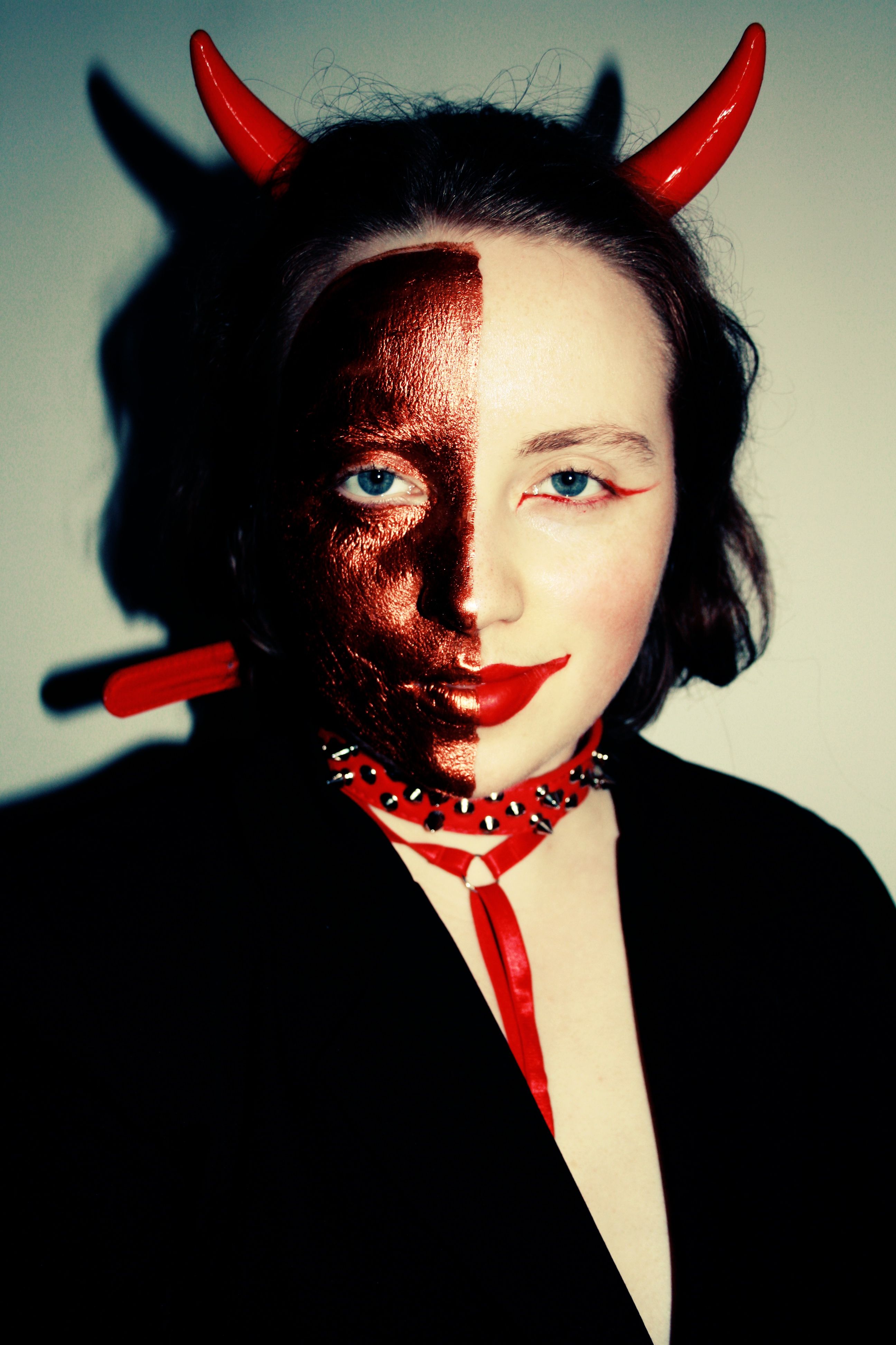 A captivating half-face makeup portrait with devil horns, perfect for Halloween themes.