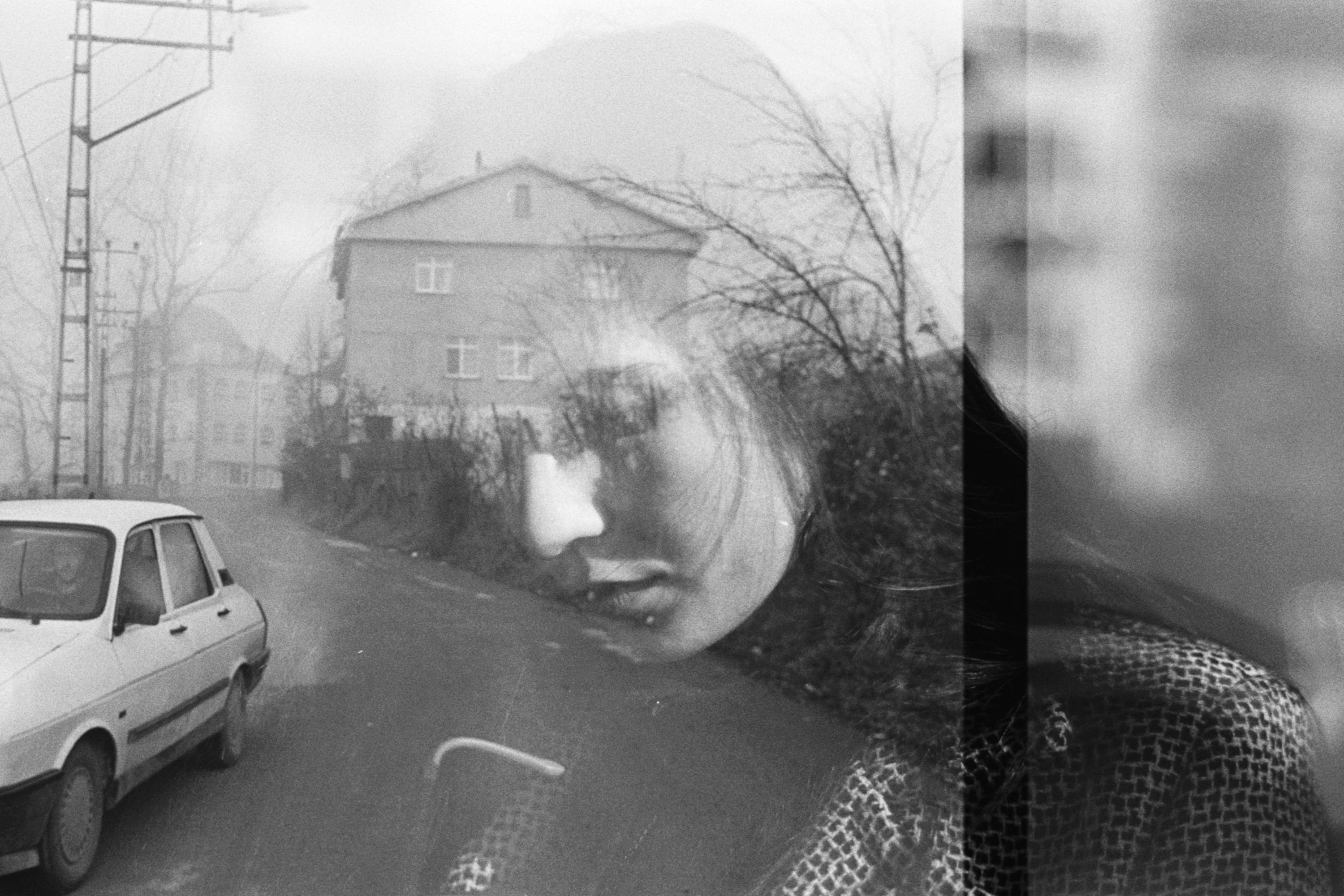 Artistic black and white double exposure of a woman's face with a city street.