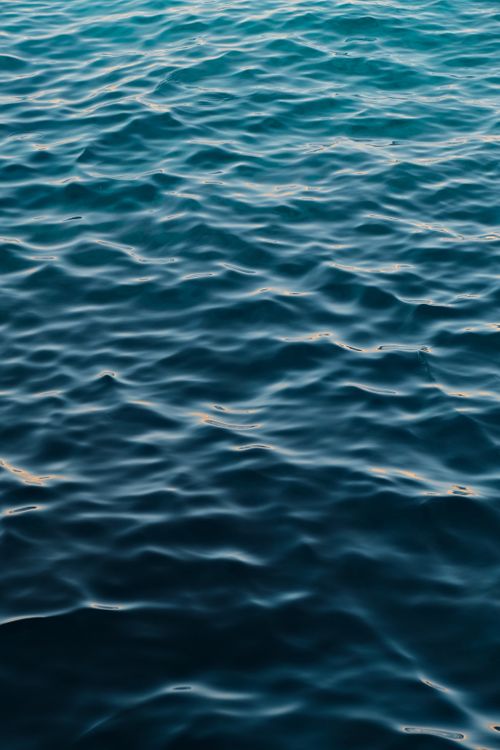 Free Peaceful ocean waves ripple under sunlight, creating a soothing abstract pattern. Stock Photo