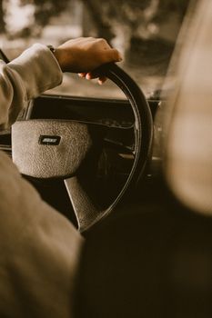 Close-up of a hand on the steering wheel in a vintage car's interior.