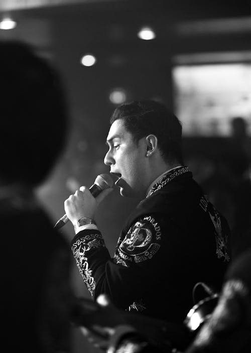Black and White Photo of a Man Singing at a Concert 