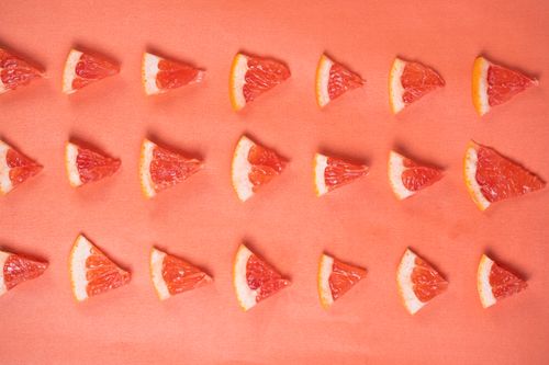 Free Array of juicy grapefruit slices on a cheerful pink surface, perfect for health and summer themes. Stock Photo
