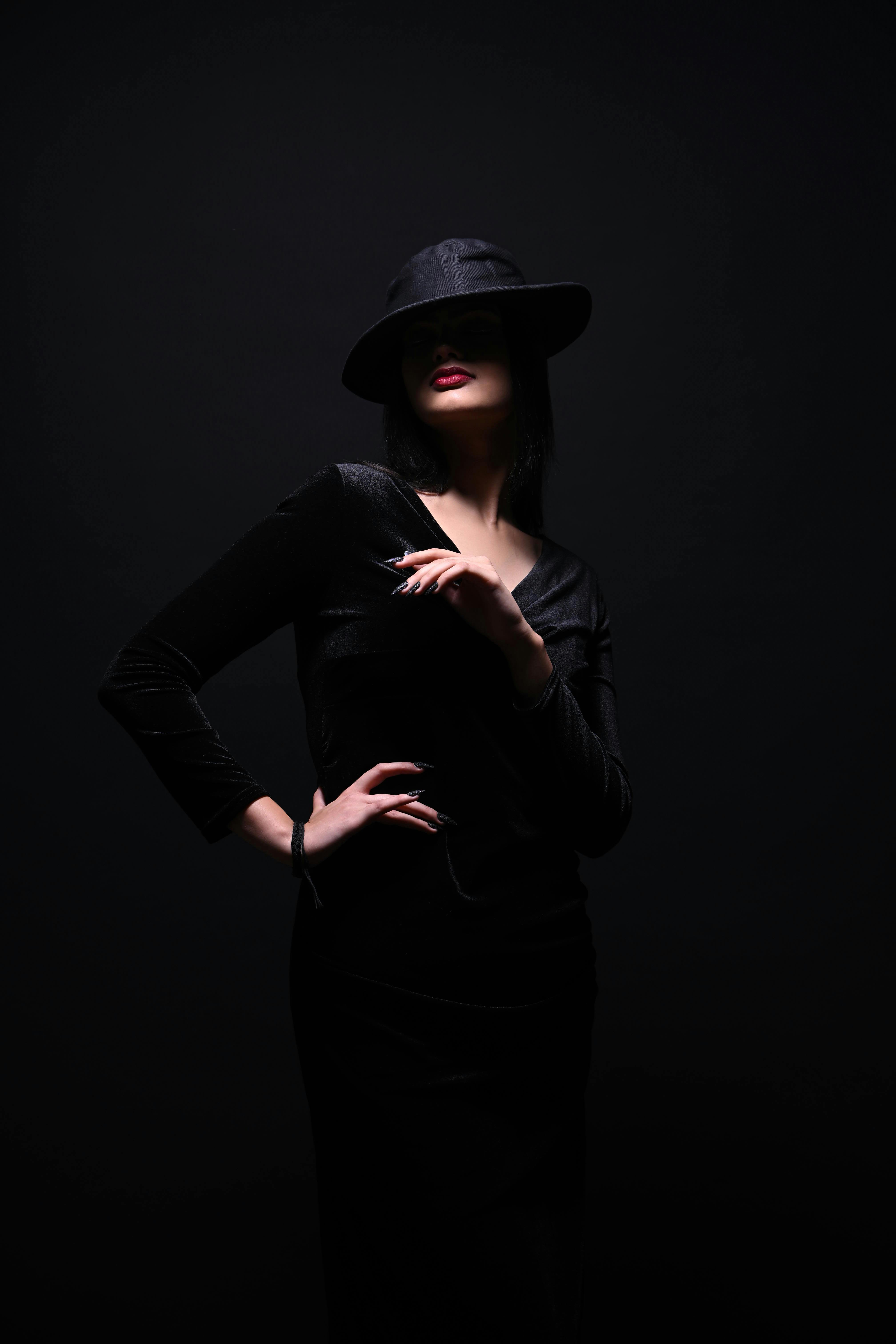Chic fashion portrait of a woman in a black hat and dress, exuding mystery.