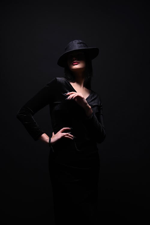 A woman in a black dress and hat