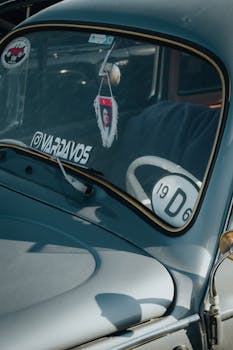 Detailed view of a classic car's windshield with retro stickers and interior decor.