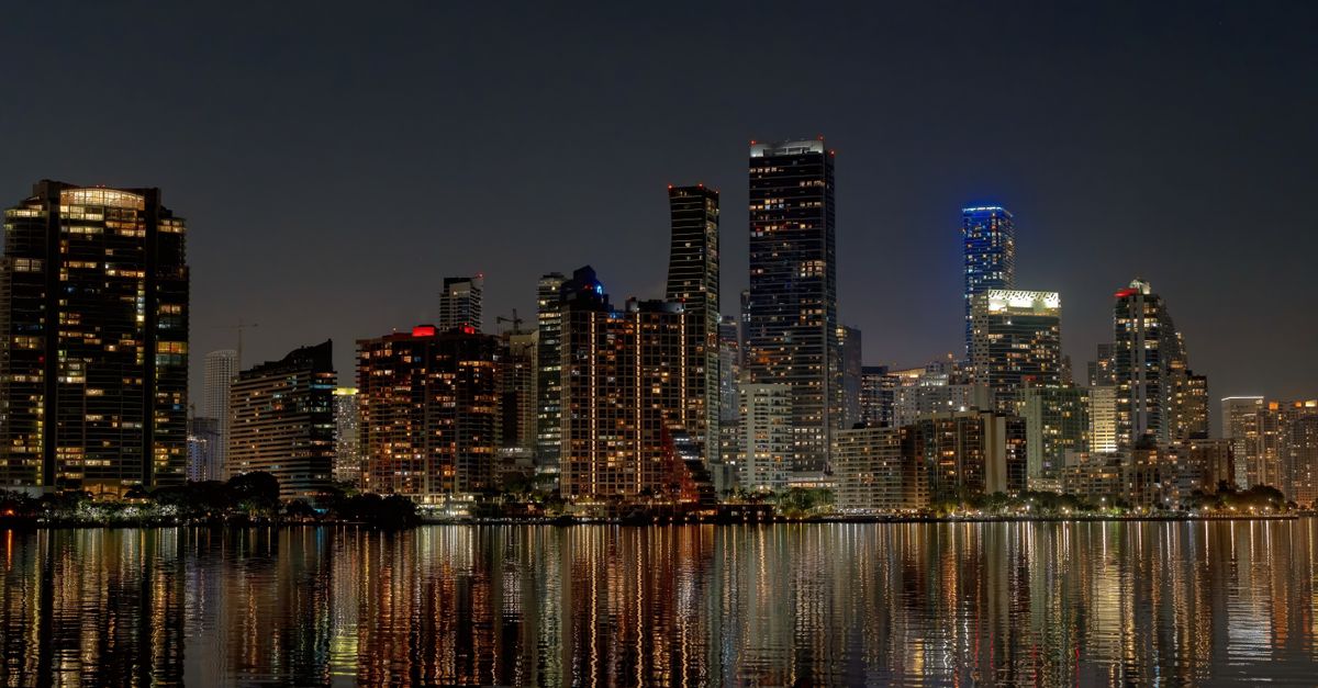 Explore the vibrant Miami skyline at night with stunning reflections in the water.
