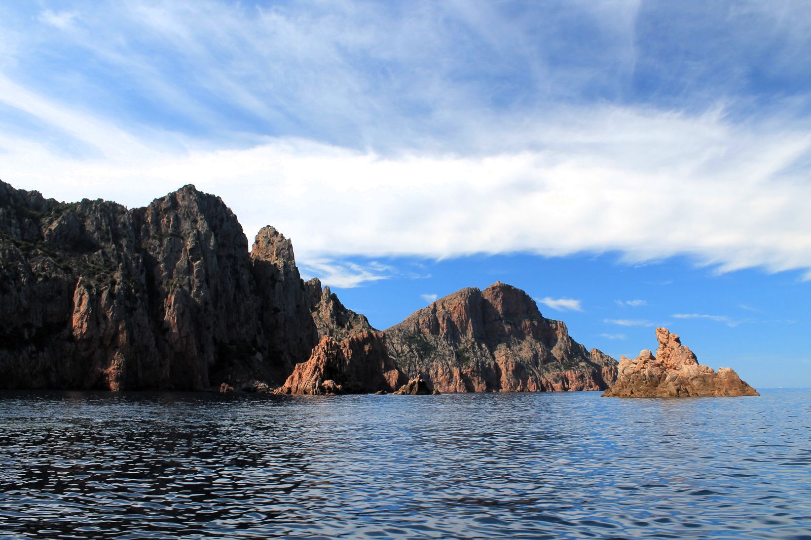 Red granite cliffs of the Scandola reserve rising straight from the Corsican sea