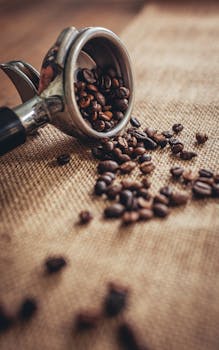 Close-up shot of coffee beans spilling from a portafilter onto a burlap surface, highlighting texture and freshness.