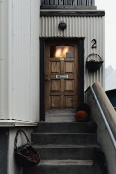 A mysterious wooden doorway with a carved pumpkin and basket on a concrete stairway.