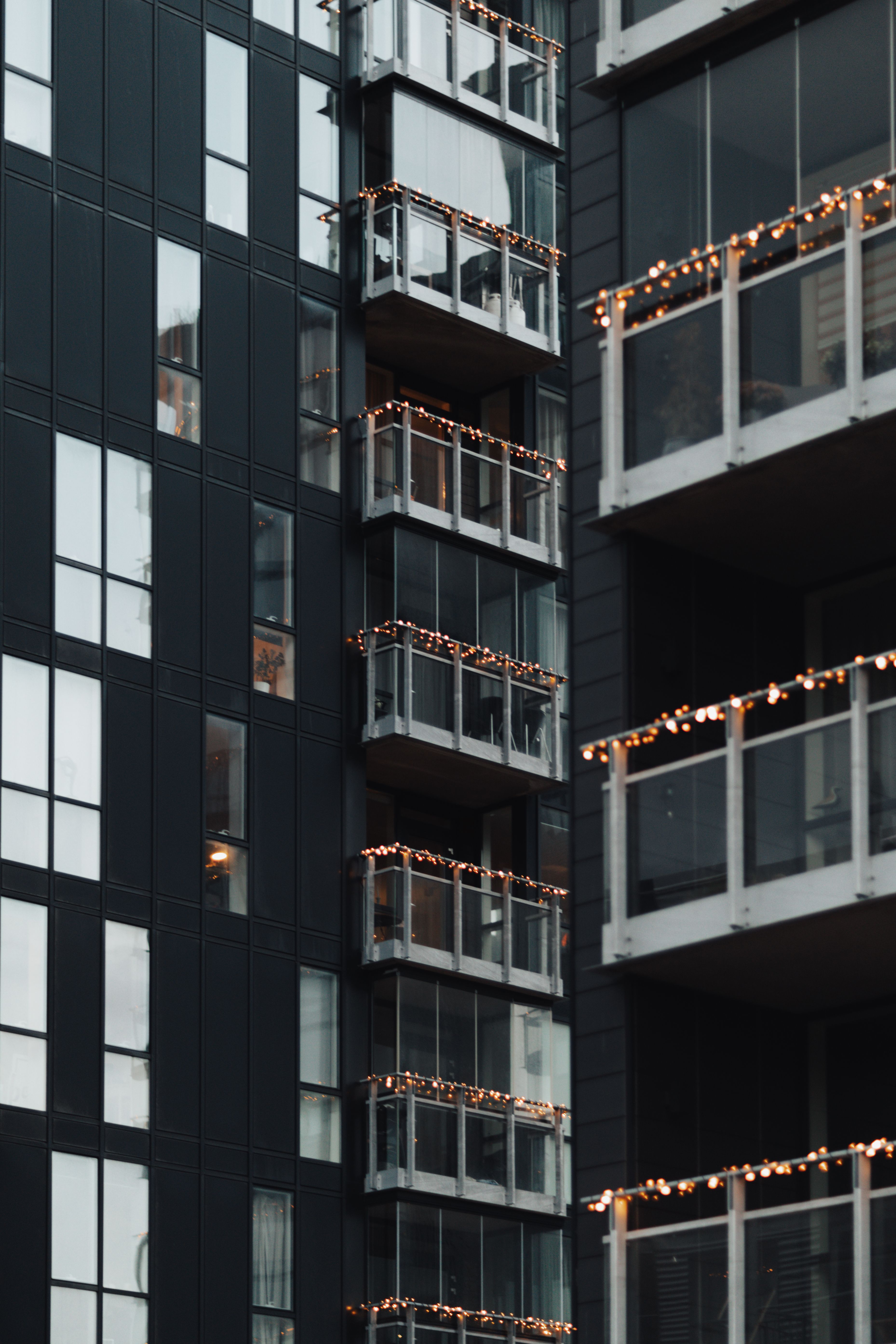 Contemporary apartment buildings adorned with festive lights on the balconies during winter.