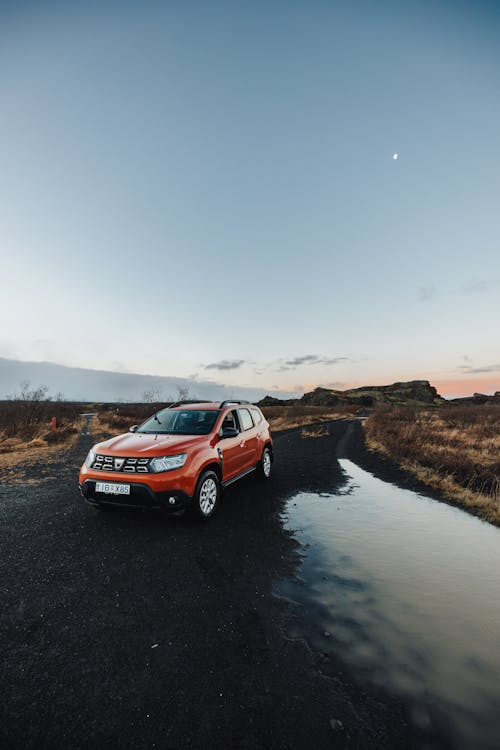 Red Dacia Duster Next to a Puddle on the Road