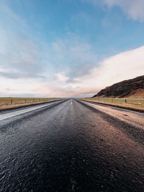 Free Empty road stretches through the scenic plains of Rangárþing eystra, Iceland, under a vivid sky. Stock Photo