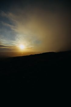Silhouette of a rural landscape at sunset with dramatic clouds and vivid colors.