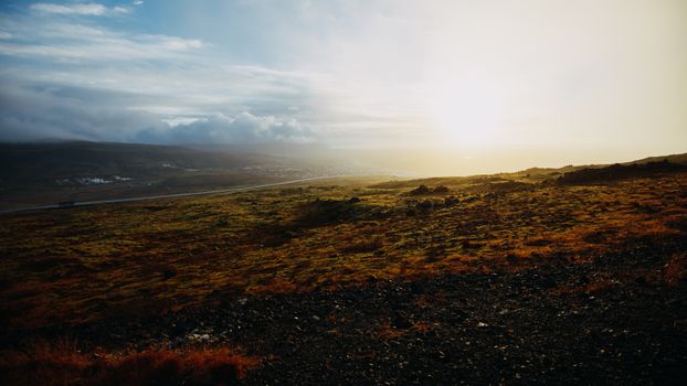 Breathtaking view of a misty countryside landscape during sunset with a road and distant hills.