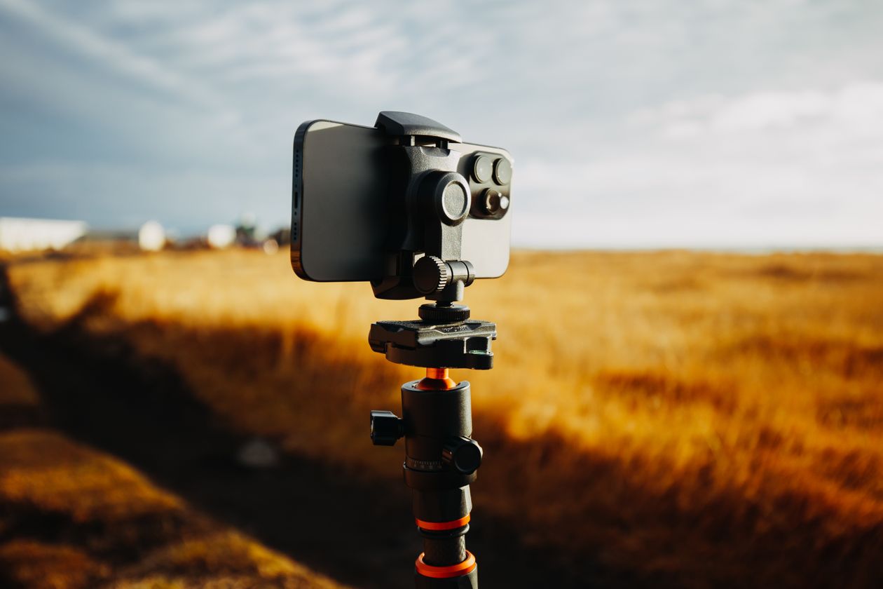 A smartphone mounted on a tripod in a golden field