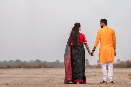 Back View of Couple in Traditional Clothing Holding Hands