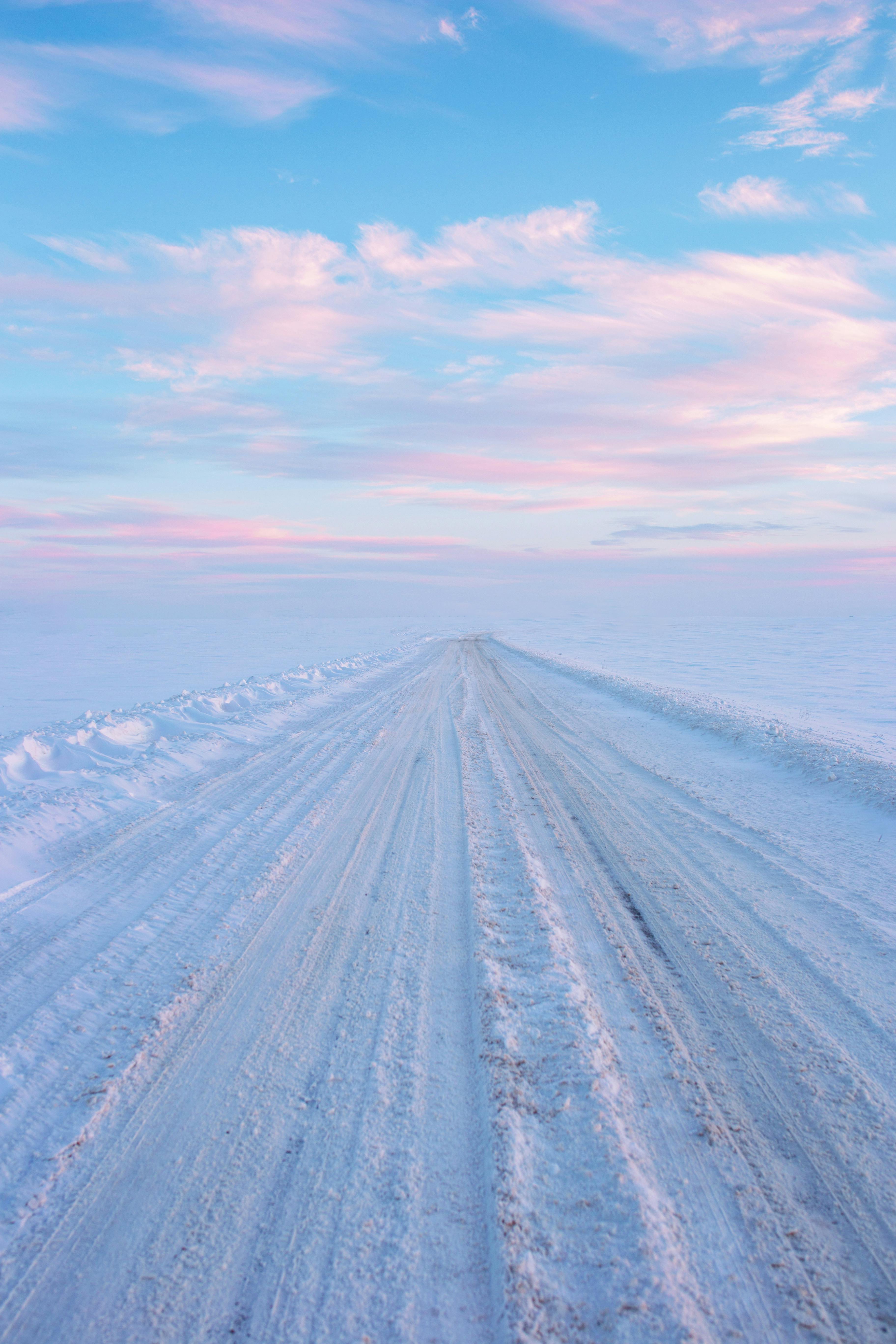 A serene snow-covered dirt road stretches under a colorful sky in Mogilev, Belarus.