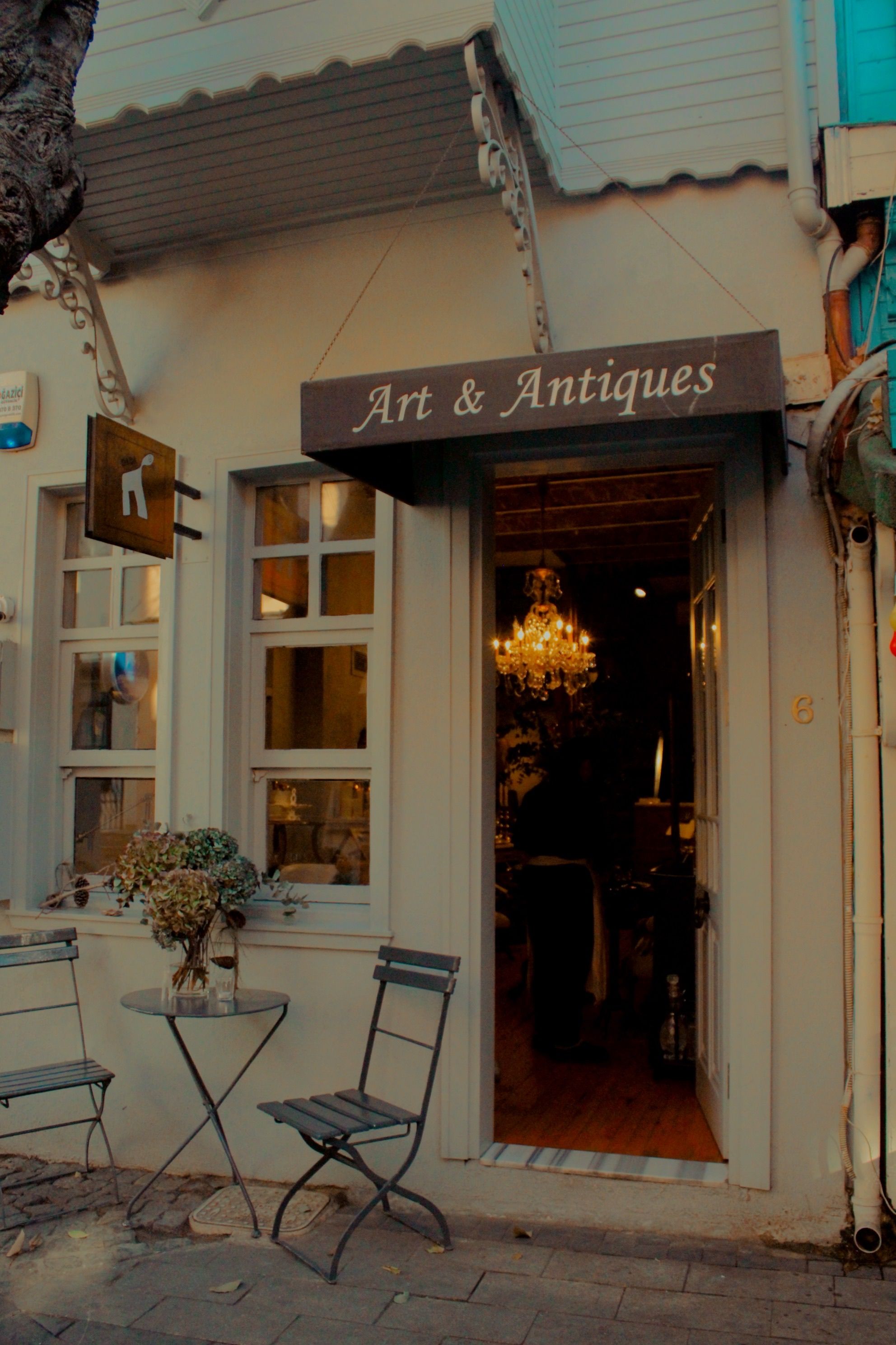 Elegant antique shop entrance with outdoor seating in a quaint urban setting.