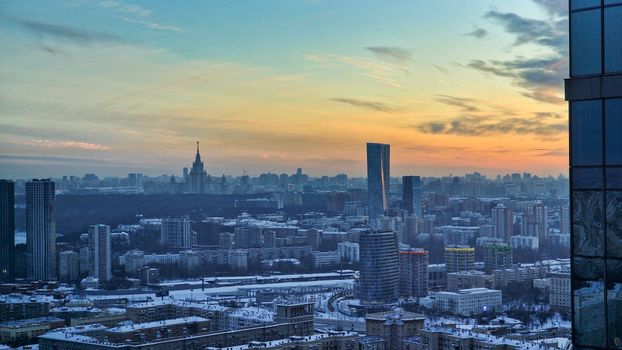 Captivating winter cityscape view with snow and stunning sunset hues over urban skyline.