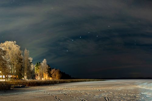 Free A serene snowy night scene in the countryside with visible stars and trees, capturing winter tranquility. Stock Photo
