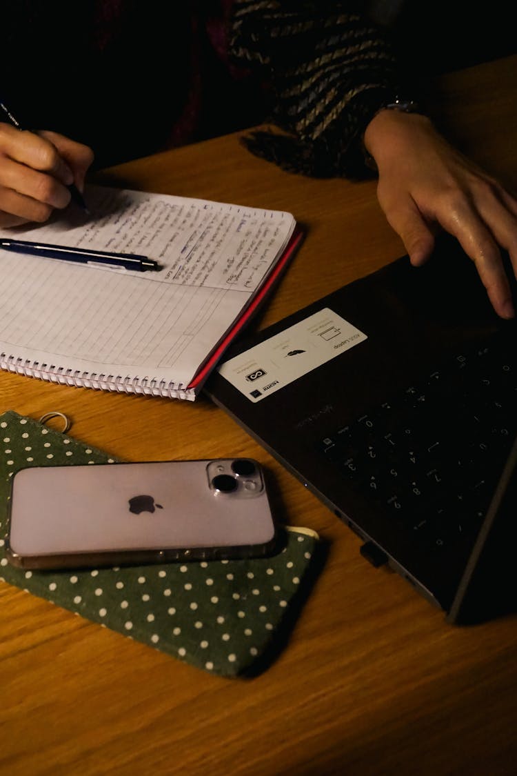 Hands Writing In Notebook And Typing On Laptop