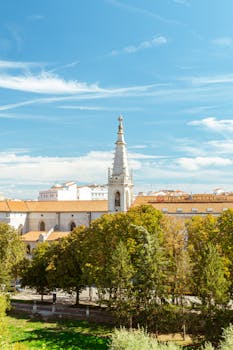 Scenic view of a historic church tower in Burgos, Spain, with lush trees under a bright sky.